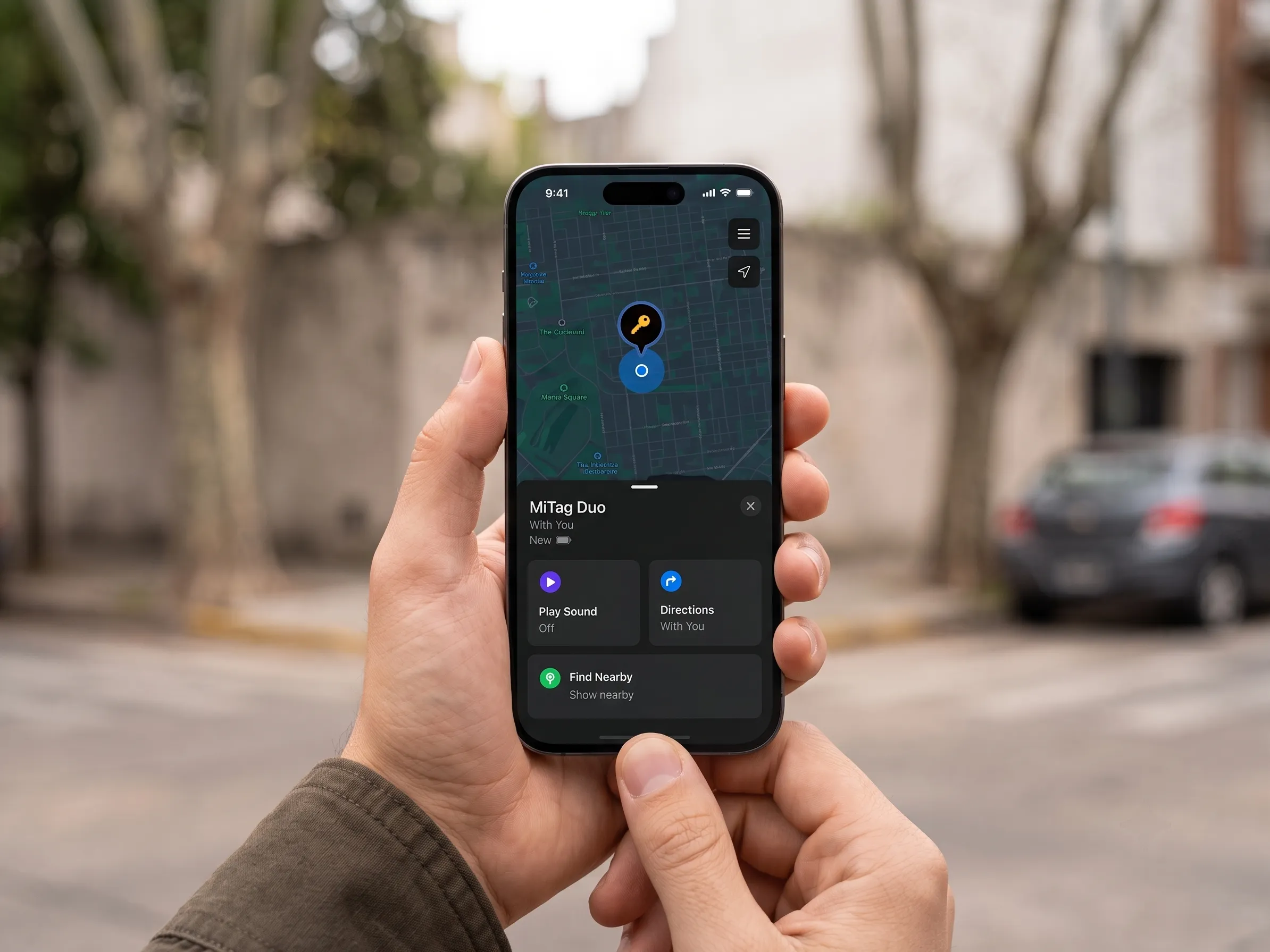 Mano sosteniendo un teléfono en la calle, con la ubicación de un MiLi MiTag Duo señalada en un mapa. Imagen de pantalla simulada.