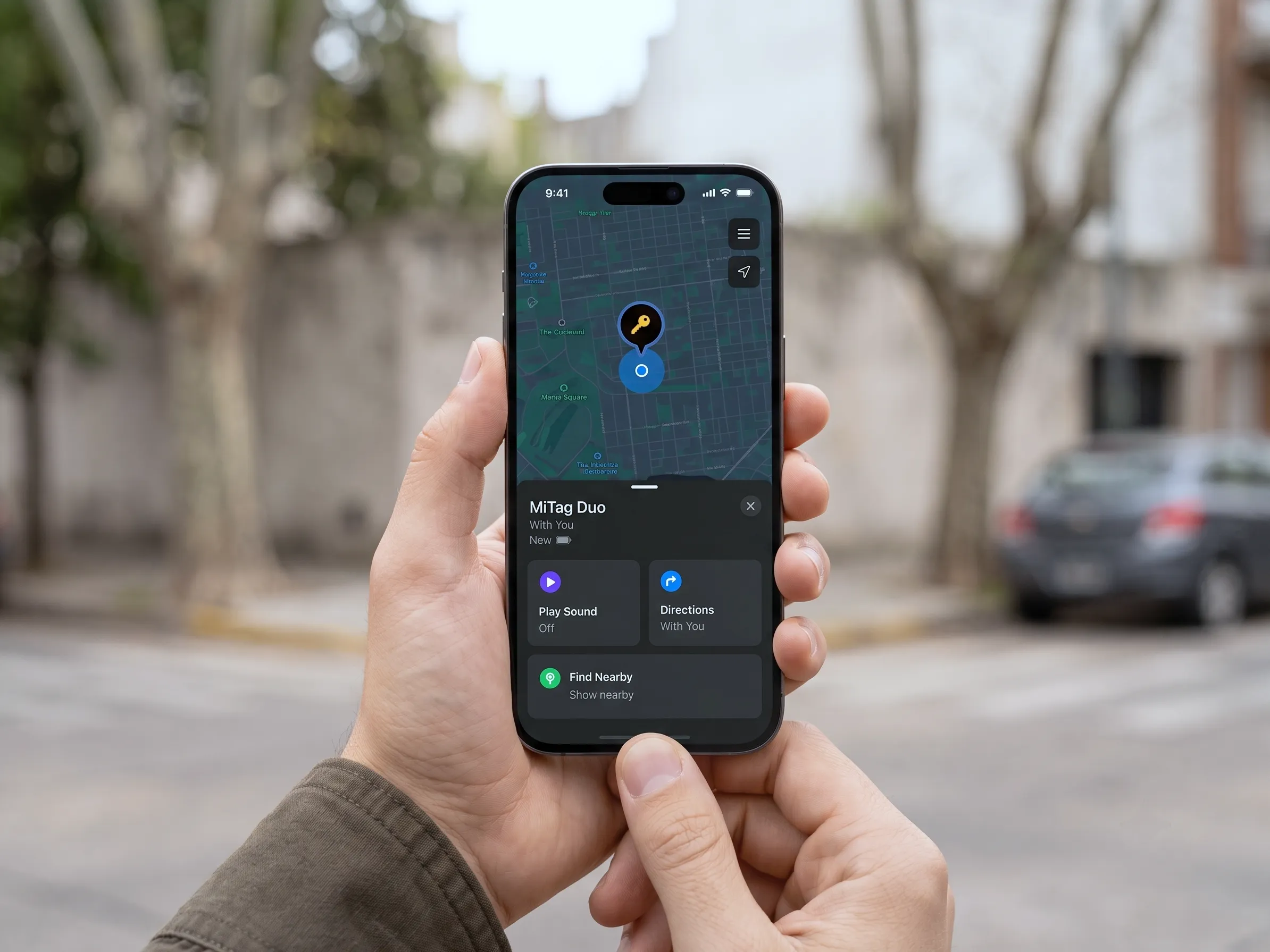 Mano sosteniendo un teléfono en la calle, con la ubicación de un MiLi MiTag Duo señalada en un mapa. Imagen de pantalla simulada.